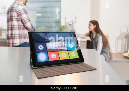 Father and daughter in kitchen behind smart home automation system on digital tablet Stock Photo