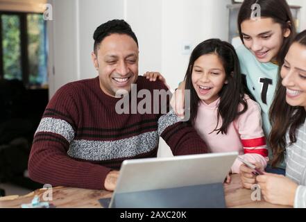 Happy family using digital tablet at table Stock Photo