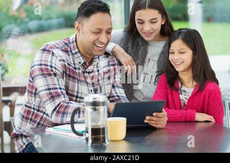 Happy father and daughters using digital tablet in morning kitchen Stock Photo