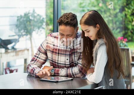 Father and daughter using digital tablet in kitchen Stock Photo