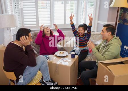 Happy friends taking a break from moving, playing cards Stock Photo