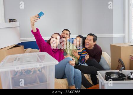 Happy friends taking a break from moving, taking selfie on sofa Stock Photo