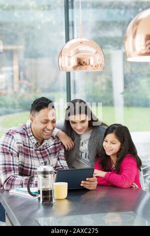 Happy father and daughters using digital tablet in morning kitchen Stock Photo