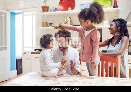 Young family playing with toy dinosaurs in kitchen Stock Photo