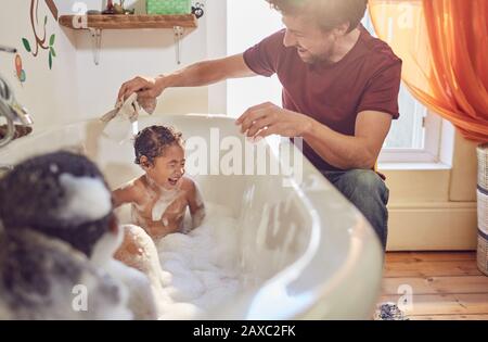 Father giving playful father giving toddler daughters bath