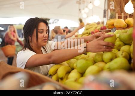 Woman working, arranging pears at farmer’s market Stock Photo