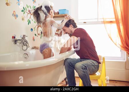 Playful father giving daughter bubble bath