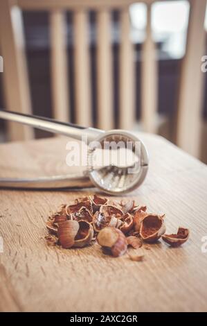 Soft focus shot of broken hazelnut nut shells on a table with a nutcracker Stock Photo