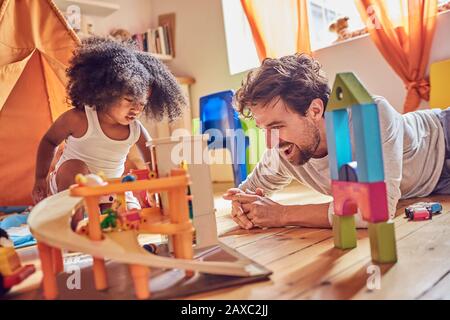 Father and toddler daughter playing with toys on floor