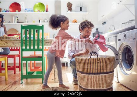 Father and daughter doing laundry in kitchen Stock Photo