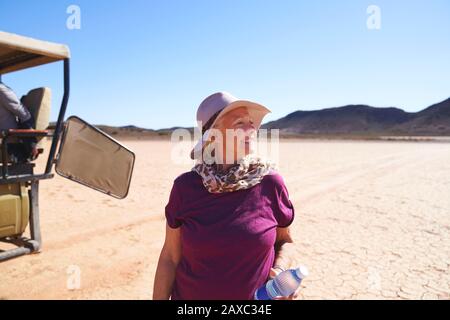 Happy senior woman on safari in sunny arid desert South Africa Stock Photo