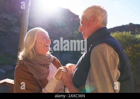 Happy senior couple holding hands on sunny balcony Stock Photo