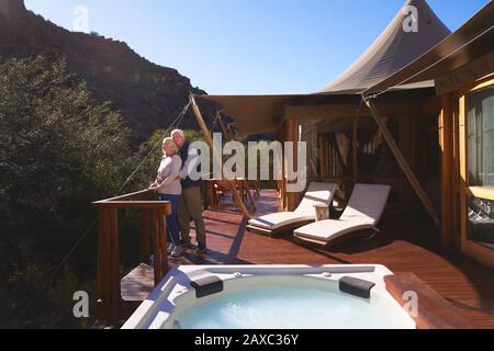 Affectionate senior couple on sunny luxury safari lodge balcony Stock Photo