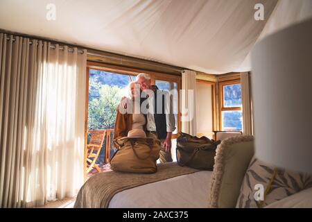 Portrait happy senior couple hugging in hotel bedroom Stock Photo