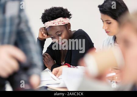 Female community college students reviewing paperwork in classroom Stock Photo