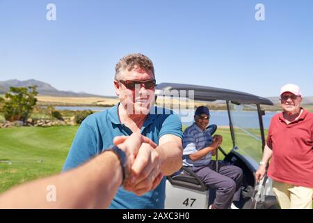 Personal perspective male golfers handshaking on sunny golf course Stock Photo