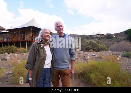 Happy senior couple outside safari lodge cabin Stock Photo