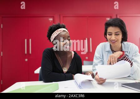 Female community college students discussing paperwork in classroom Stock Photo