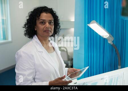 Portrait confident, determined female doctor using digital tablet in hospital room Stock Photo