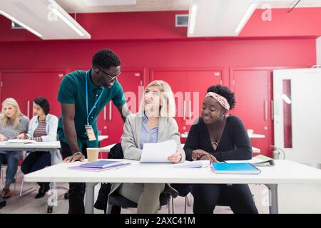 Community college instructor helping students with paperwork in classroom Stock Photo