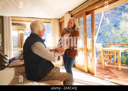 Happy senior couple holding hands in safari lodge hotel room Stock Photo