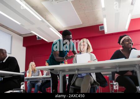 Community college instructor helping student with paperwork in classroom Stock Photo