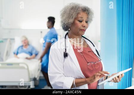 Female senior doctor using digital tablet in hospital room Stock Photo