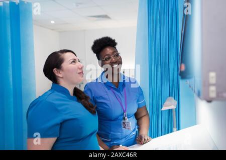 Female doctor and nurse examining x-rays in hospital room Stock Photo