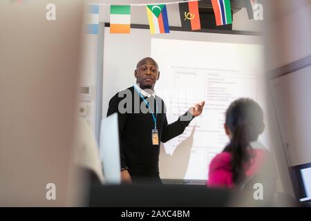 Male community college instructor leading lesson at projection screen in classroom Stock Photo