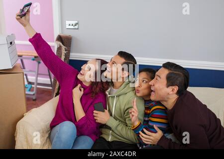 Playful friends taking a break from moving, taking a selfie with smart phone Stock Photo