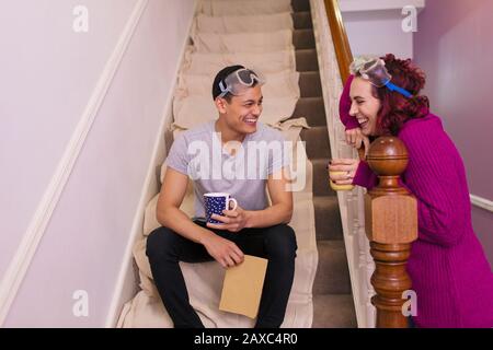 Happy couple taking coffee break from redecorating on stairs Stock Photo