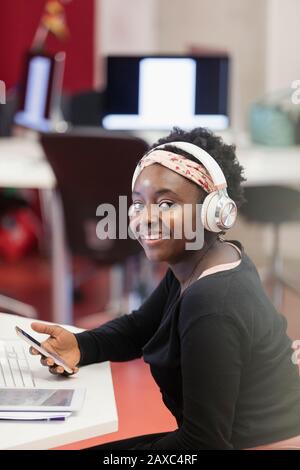 Portrait confident female student with headphones and smart phone Stock Photo