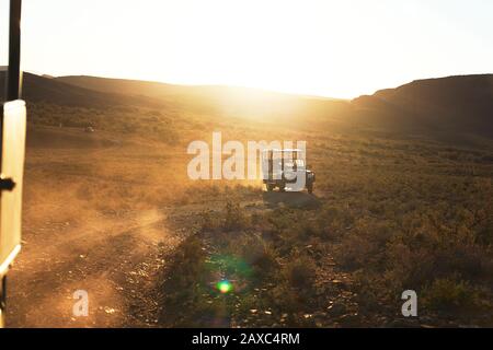 Safari off-road vehicle driving on sunny dirt road South Africa Stock Photo