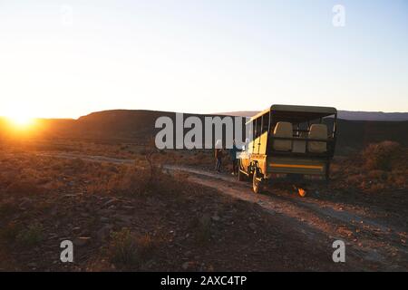 Safari off-road vehicle and tourists at sunset roadside South Africa Stock Photo