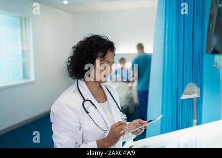 Focused female doctor using digital tablet in hospital room Stock Photo