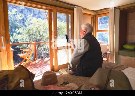 Senior man using smart phone on hotel bed Stock Photo