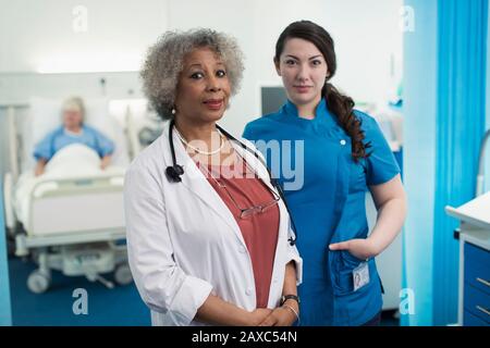 Portrait confident female doctor and nurse in hospital room Stock Photo