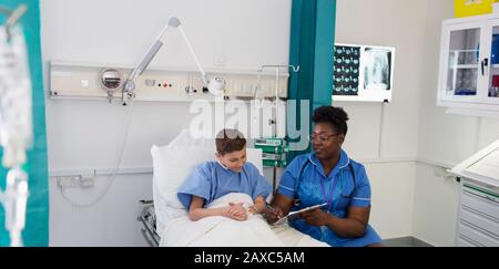 Female nurse talking with boy patient in hospital room Stock Photo