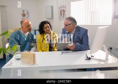 Doctors and administrator using digital tablet, meeting in doctors office Stock Photo