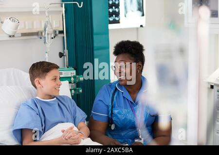 Female nurse talking with boy patient in hospital room Stock Photo