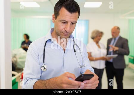Male doctor using smart phone in hospital ward Stock Photo