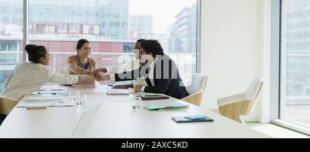 Business people joining hands in conference room meeting Stock Photo