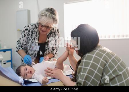 Female pediatrician examining baby girl on examination room table Stock Photo