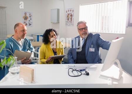 Doctors and administrator meeting at computer in doctors office Stock Photo