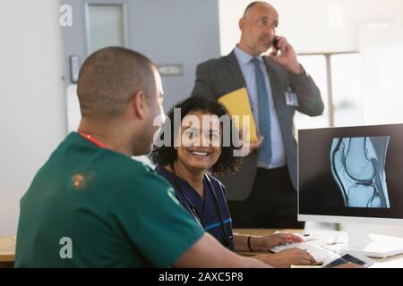 Smiling nurses discussing digital x-ray at computer in clinic Stock Photo