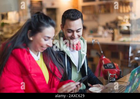 Young couple using smart phone and laptop in cafe Stock Photo