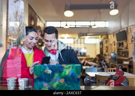 Young couple using smart phone at cafe window Stock Photo
