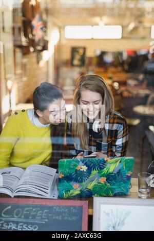Smiling young female college students studying in cafe Stock Photo