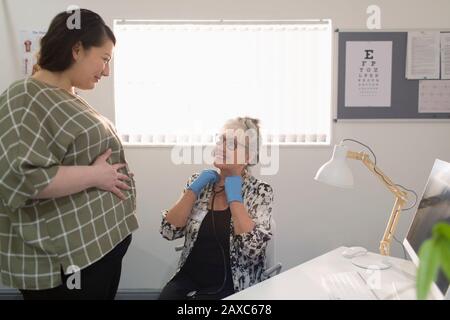 Female doctor examining pregnant woman in doctors office Stock Photo