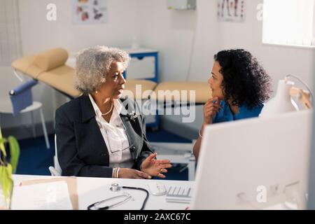 Female doctor talking with senior patient in doctors office Stock Photo